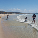 Image of a few kids playing in the shallow water on a beach having fun in the shallow water