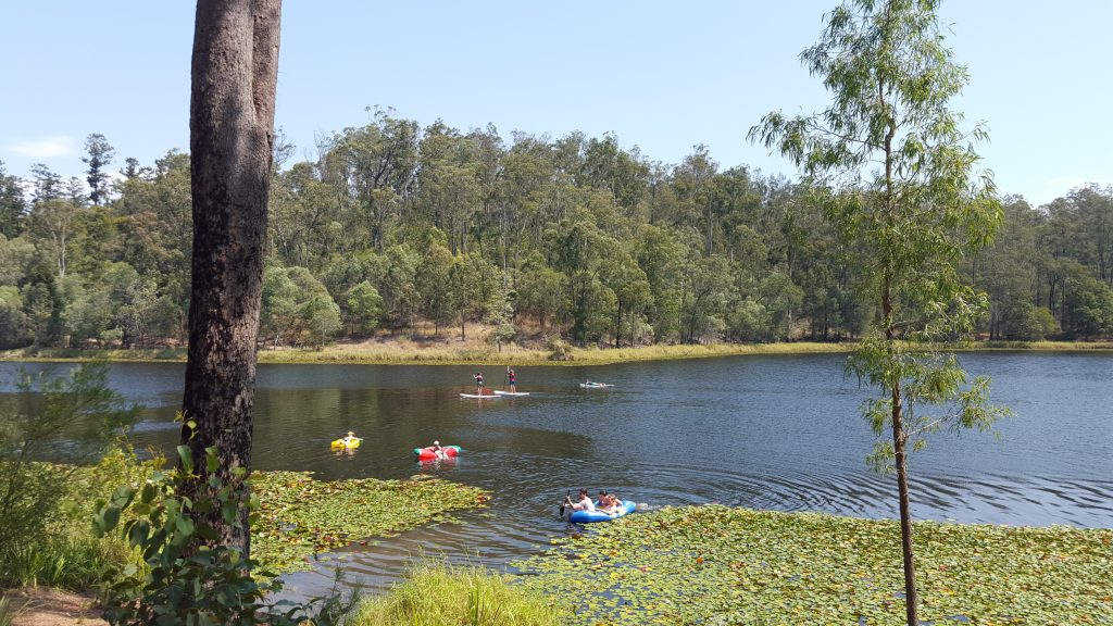 Image of a reservoir with three kayaks paddling across the surface