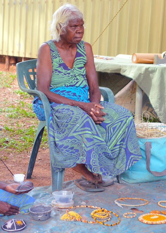 Image of a seated indiegnous woman wearing a blue and green dress
