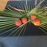 Image of \fFour orange Kakadu plum fruits on top of green pandansu leaves on a table
