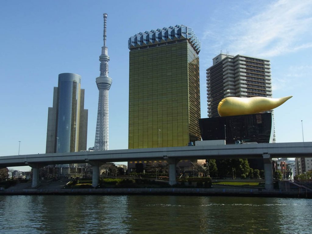 Image of some freestanding buildings in Tokyo one has a large sculpture in teh shape of golden turd