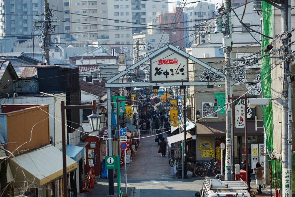 The entrance to a series of shops with tall buildings behind