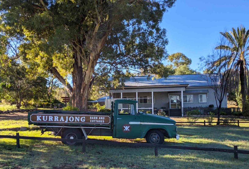 Image of an old green ute parked in front of an large renovated barn