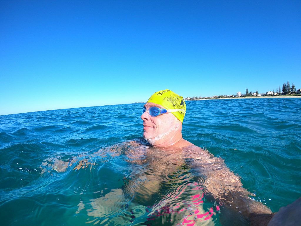 Image of a man wearing a yellow bathing cap treading water in the ocean