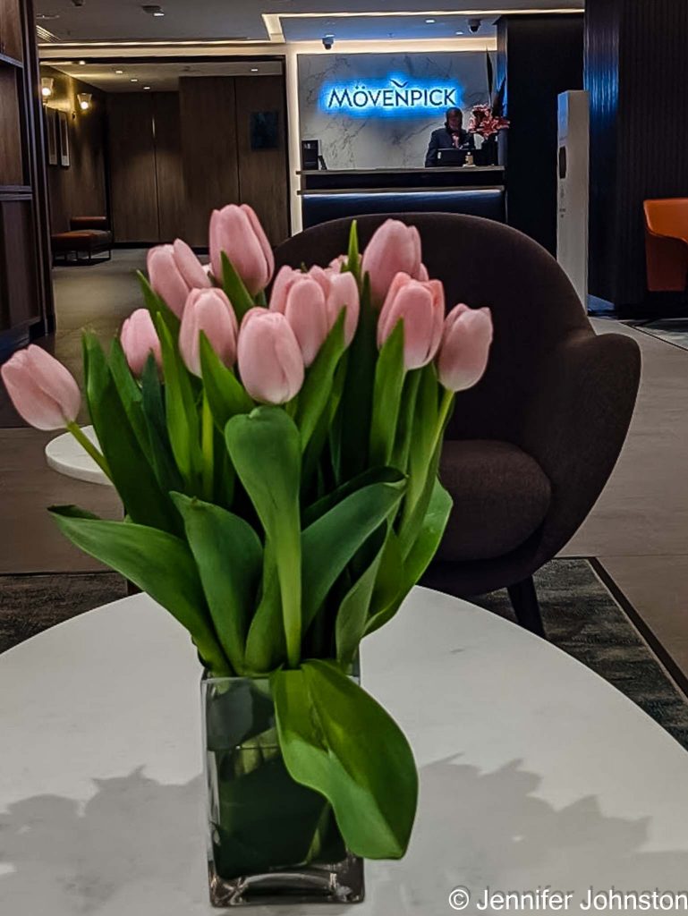Image of a vase of flowers containing a bunch of pink tulips in the background is a counter