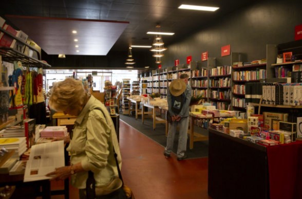 Image of a couple of people standing in a small bookstore looking at a range of books