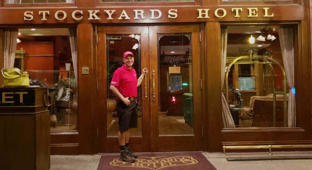 Image of a man holding the gold handle of a large hotel door