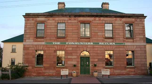Image of an old sandstone building with a sign saying The Foxhunters Return on the front
