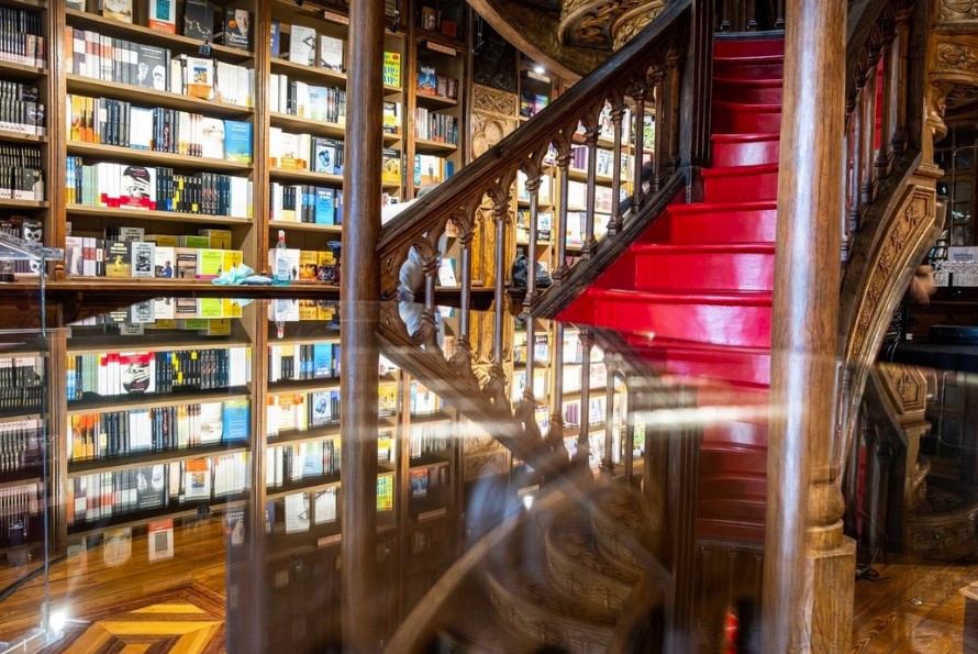 Image of an old wooden staircase with steps painted red and bookshelves behind the staircase