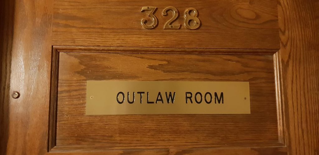 Image of a timber door with the number 328 and a brass sign saying Outlaw Room