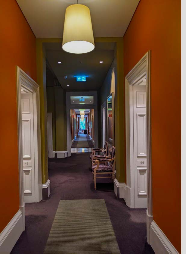 Image of a long corridor with doors on either side and rust coloured carpet on the hallway floor