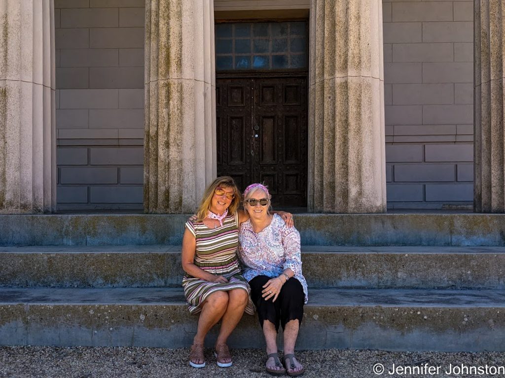 Image of two women sitting on stone steps they have their arms aorund each other