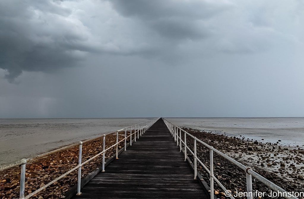 Image of long wooden jetty and a stormy sky