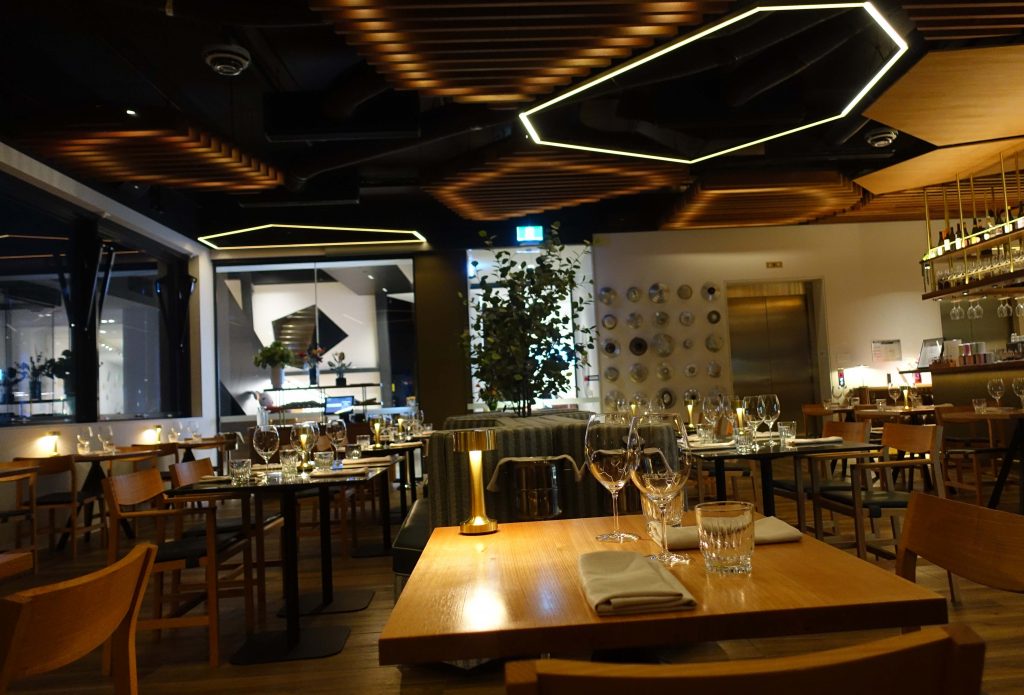 Image of the interior of a restaurant at night time with tables set for dinner