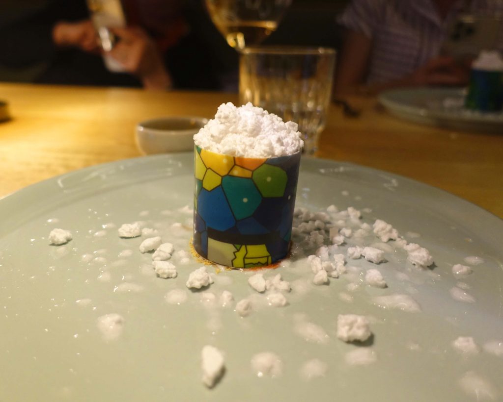 Image of a dessert that is a bright coloured case with balls of white meringue on the top