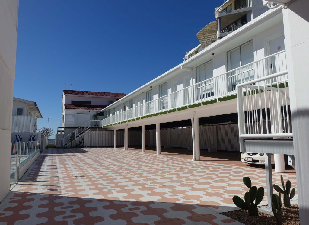 Image of a 1950s style motel building where the upstairs rooms are painted white
