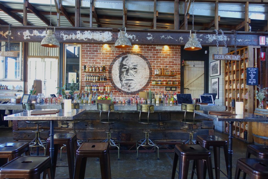 The image of the interior of bar with a brick wall at the back and lots of bottles on shelves