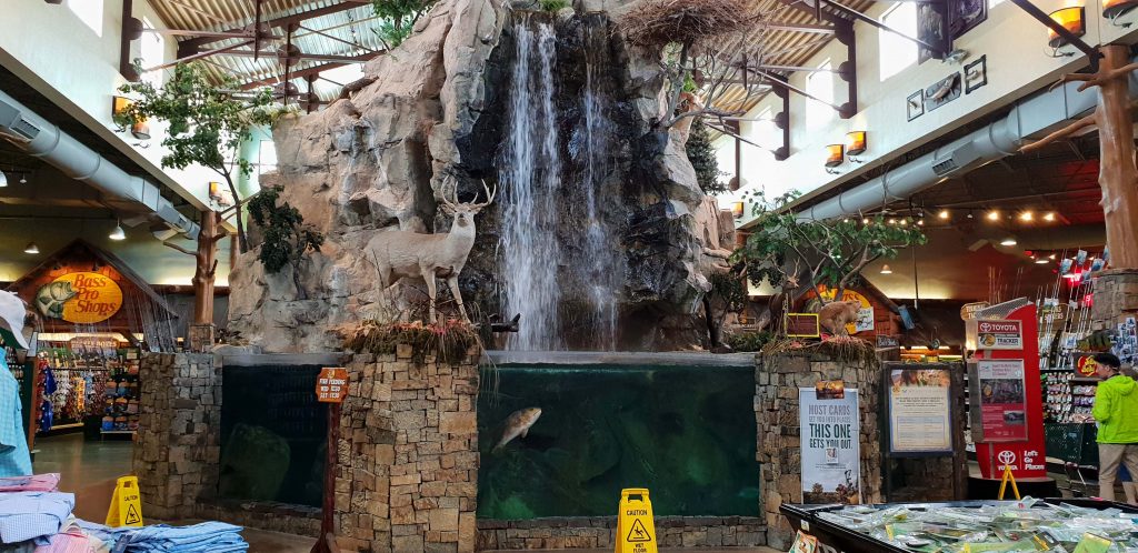 Image showing a man made waterfall with a large fish tank where the water is falling in.. This is inside a large outdoor shop.