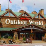 Image of the outside of a large shop brown timber walls and a green roof with the words Outdoor World in large white writing across the front
