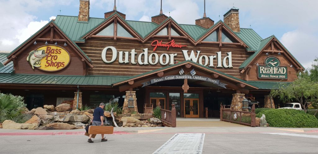 Image of a man walking into an outdoor store he is carrying a brown case