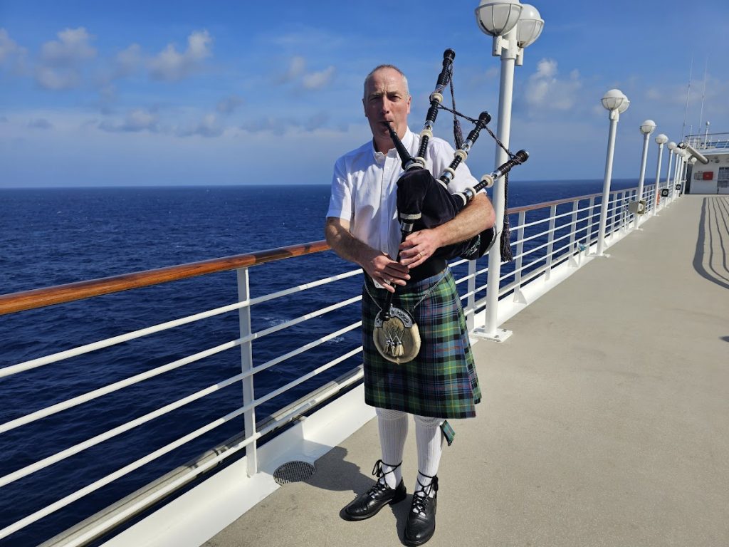 Image of a Scottish piper dressed in full kilt playing a set of bagpipes