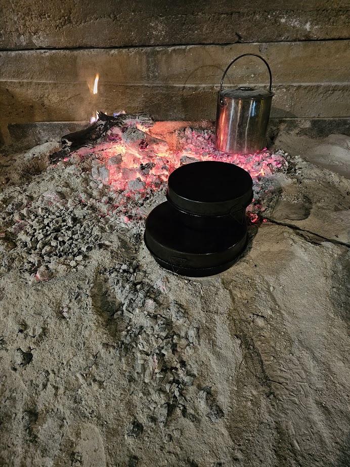 Image of some heavy cooking pans on the embers of a fire
