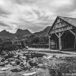 Image of an old timber boathouse with two mountain peaks in the background