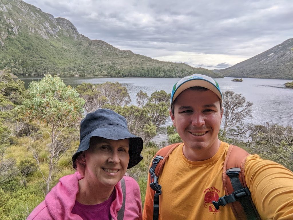 Image of an older woman and a younger man taking a selfie while hiking standing on a hiking trail taking a selfie