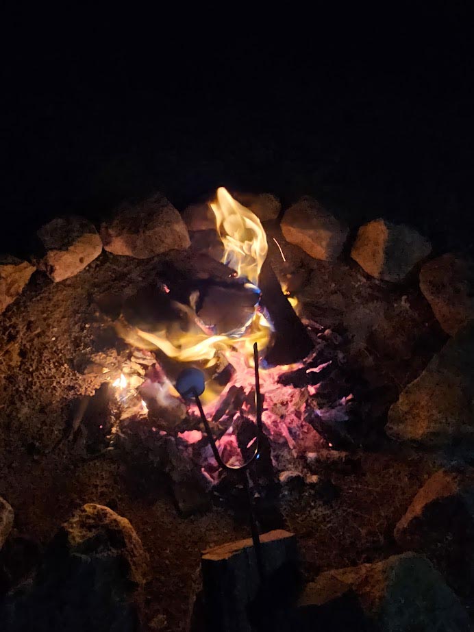 Images of marshmallows on a toasting fork over an open fire 